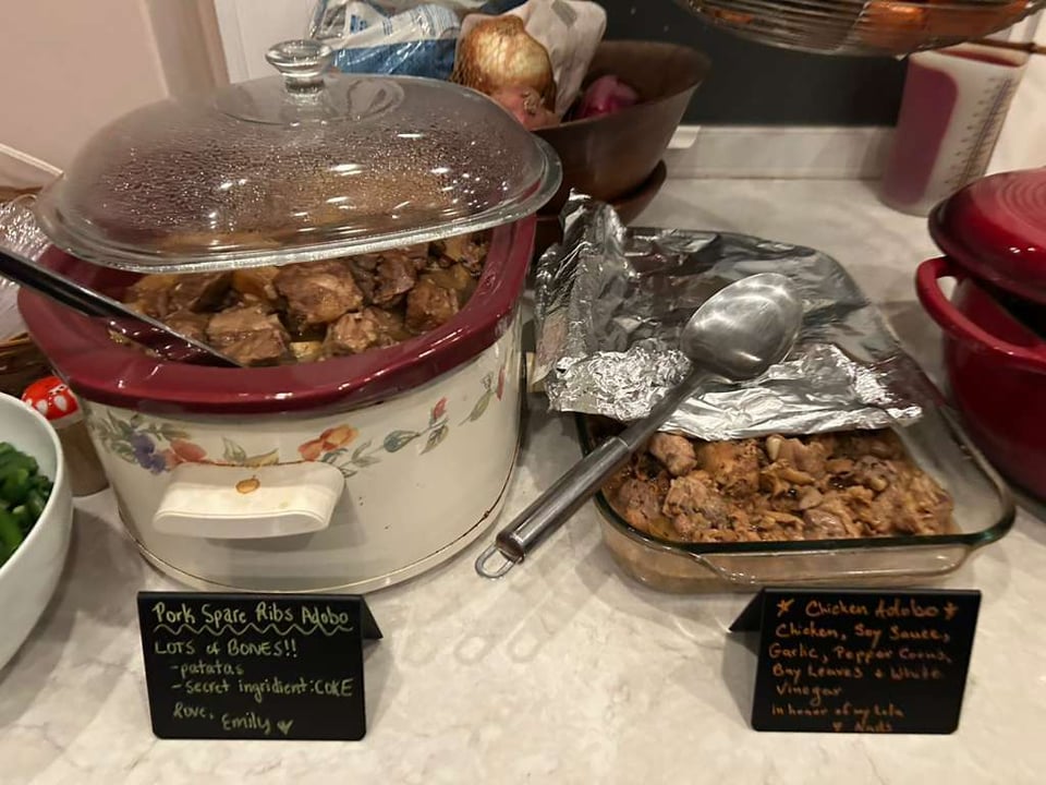 a crockpot and a pan of two different kinds of adobo plus little cards with descriptions of what's in the adobo