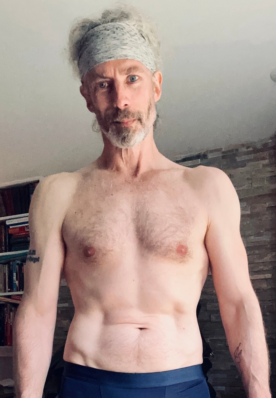 Photo of shirtless white man from waist up, with a gray headband. For his mid-50s, he looks pretty good