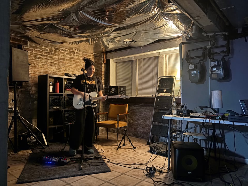 My friend Adriana playing guitar in her unfinished basement. The lighting is a little bit moody.