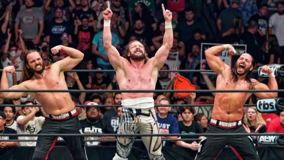 The Elite, Kenny Omega and the Young Bucks, pose in the center of the wrestling ring.