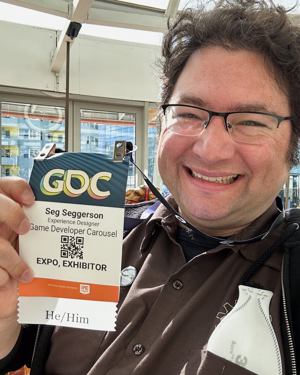 Seg holding up his GDC EXPO pass while riding the carousel.