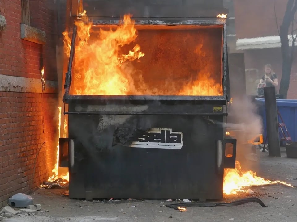 A photo of a dumpster with a fire inside