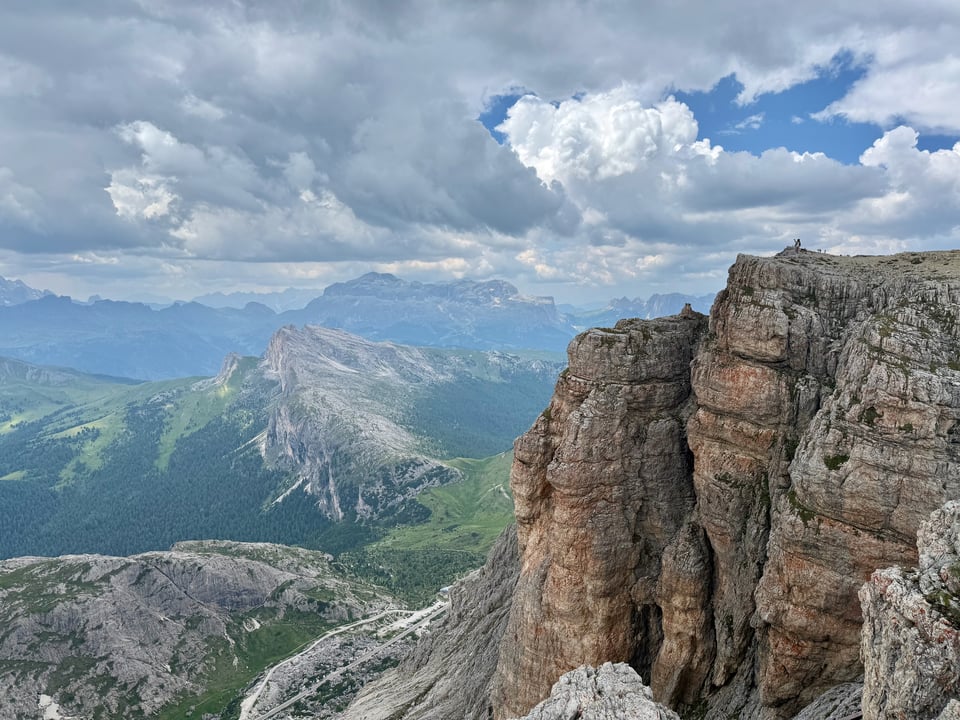 big rock with small person in the distance before a view