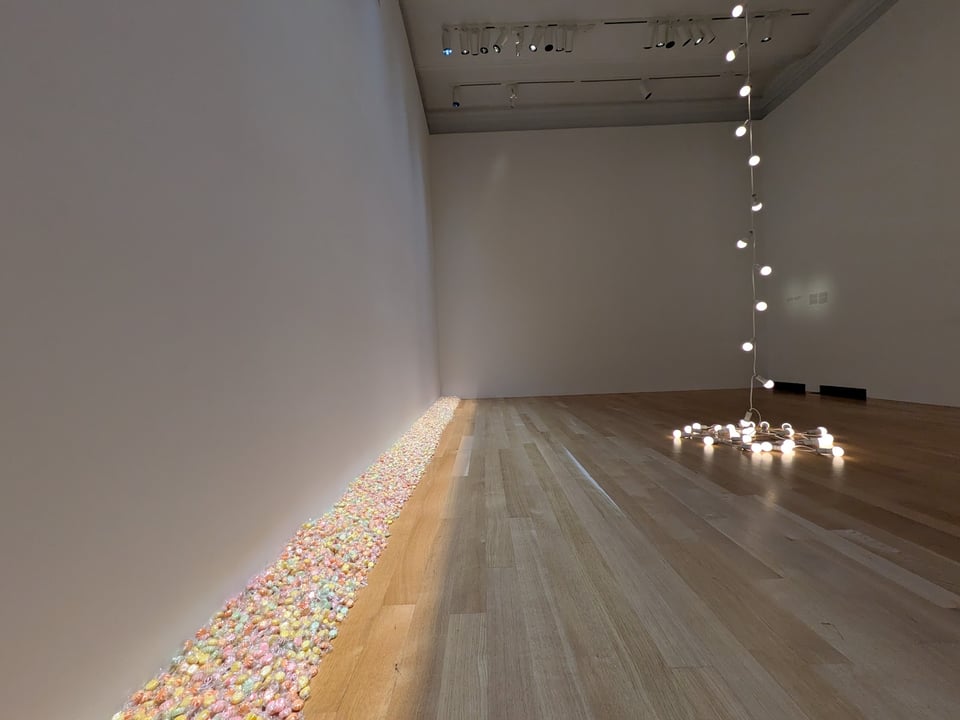 The pile of candies along the wall, lit by its own lighting system, with a string of lightbulbs in the center of the room stretching from ceiling to floor.