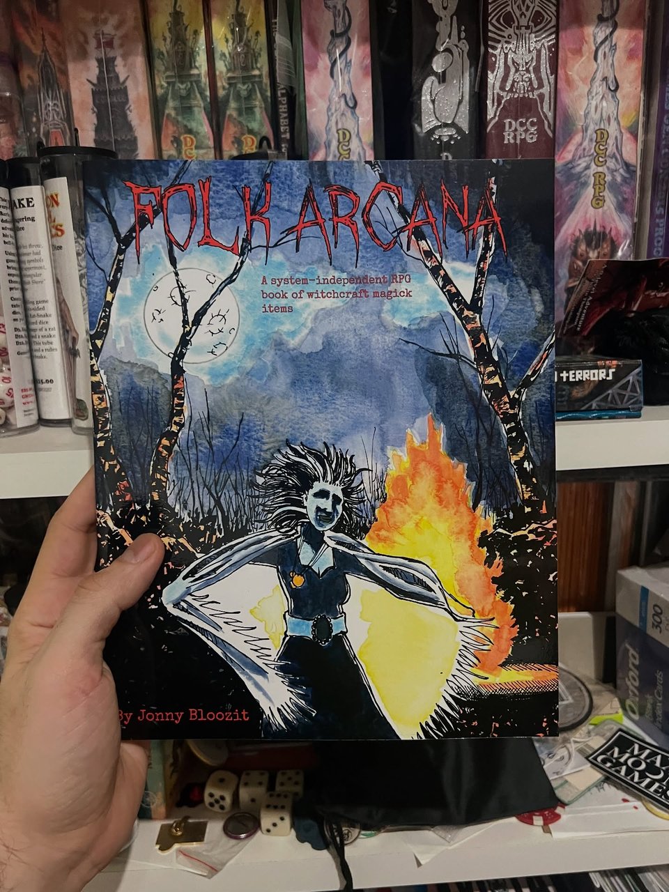 Picture of the cover of a book named Folk Arcana, showing a witch ina. dark forest, made in water color and ink with strong brushtrsokes