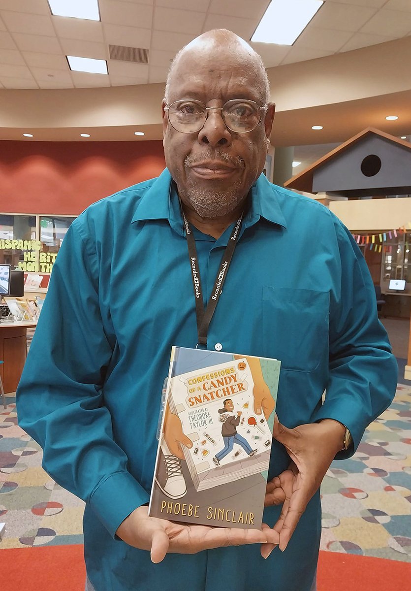 man holds book in library children's department