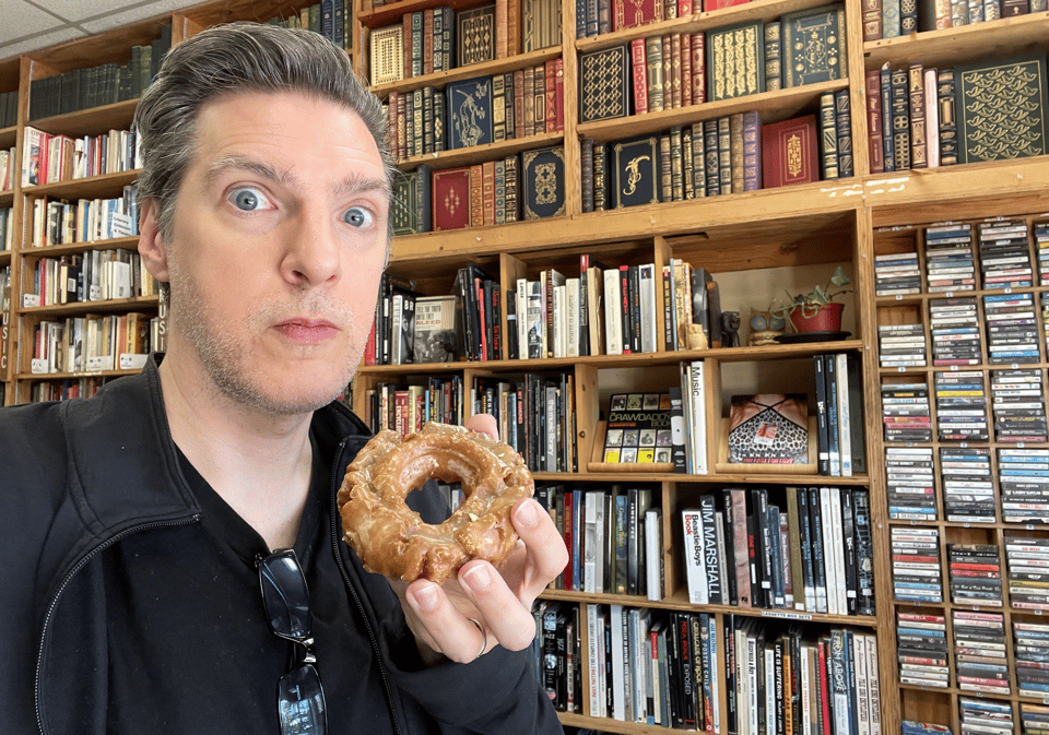 A man in a bookstore holding a donut, overwhelmed with emotion