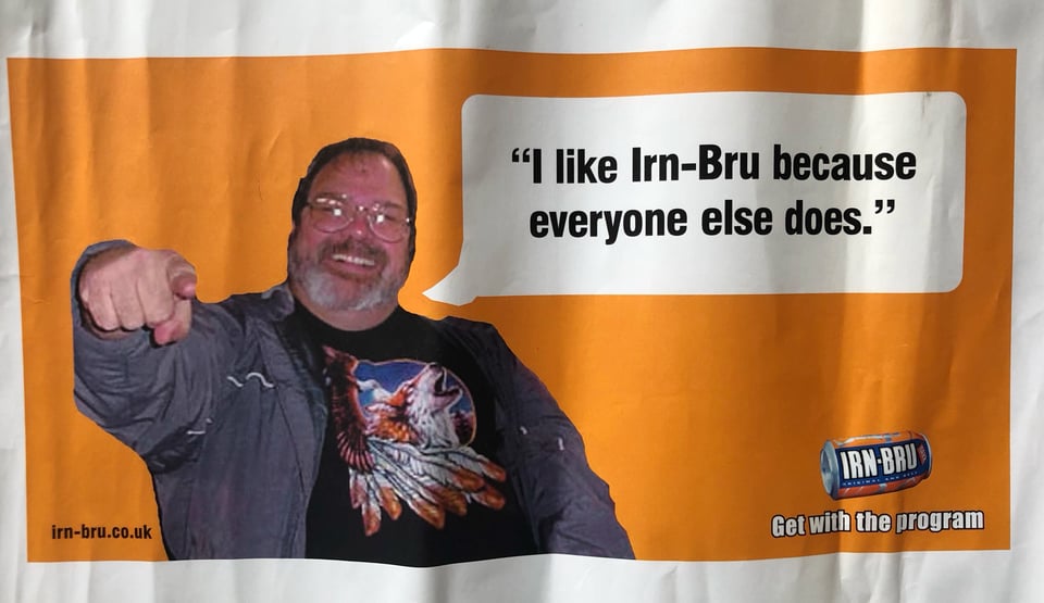 A scan of a rough presentation concept for an IRN-BRU poster advertisement. The main image is a photograph of a bearded man who's is pointing towards the camera and smiling. There is a speech bubble next to him in which the text says, "I like Irn-Bru because everyone else does." There is a picture of an IRN-BRU can at the bottom right, under which is the line, "Get with the program."