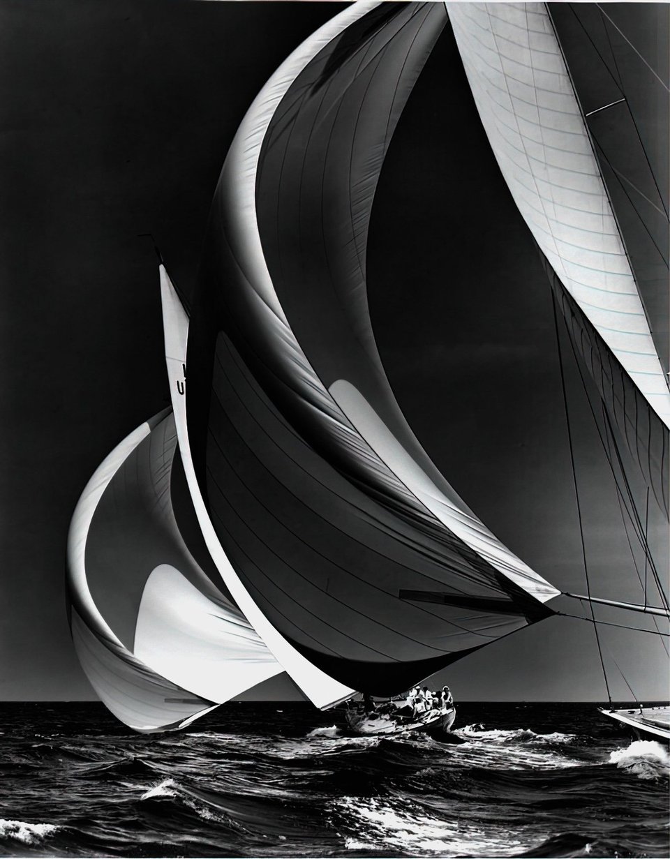 A black and white image of sail boats on a choppy sea