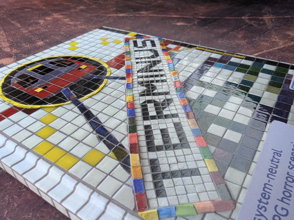 A photo of the front cover of the hardback edition of TERMINUS. The mosaic artwork looks almost 3D due to the textured gloss effect.