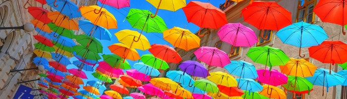 a canopy of multicolored umbrellas hung over a street between buildings