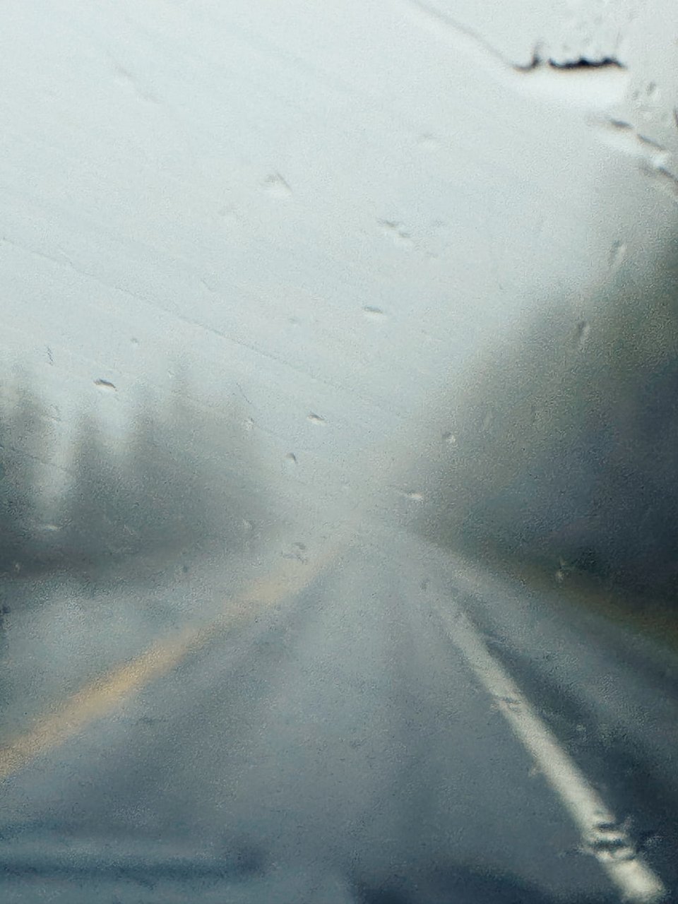 a foggy, rain covered windshield from within a moving vehicle