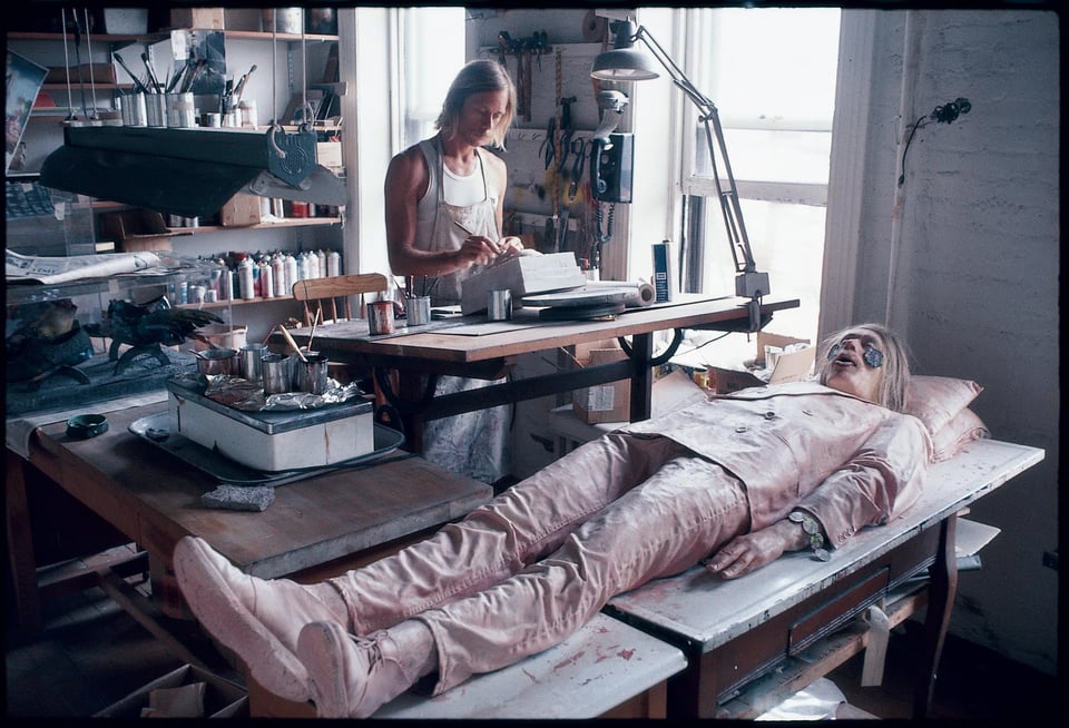 Photo by Peter Hujar of artist Paul Thek in his studio, with Paul's pink-tinted wax double lying on a table in the foreground