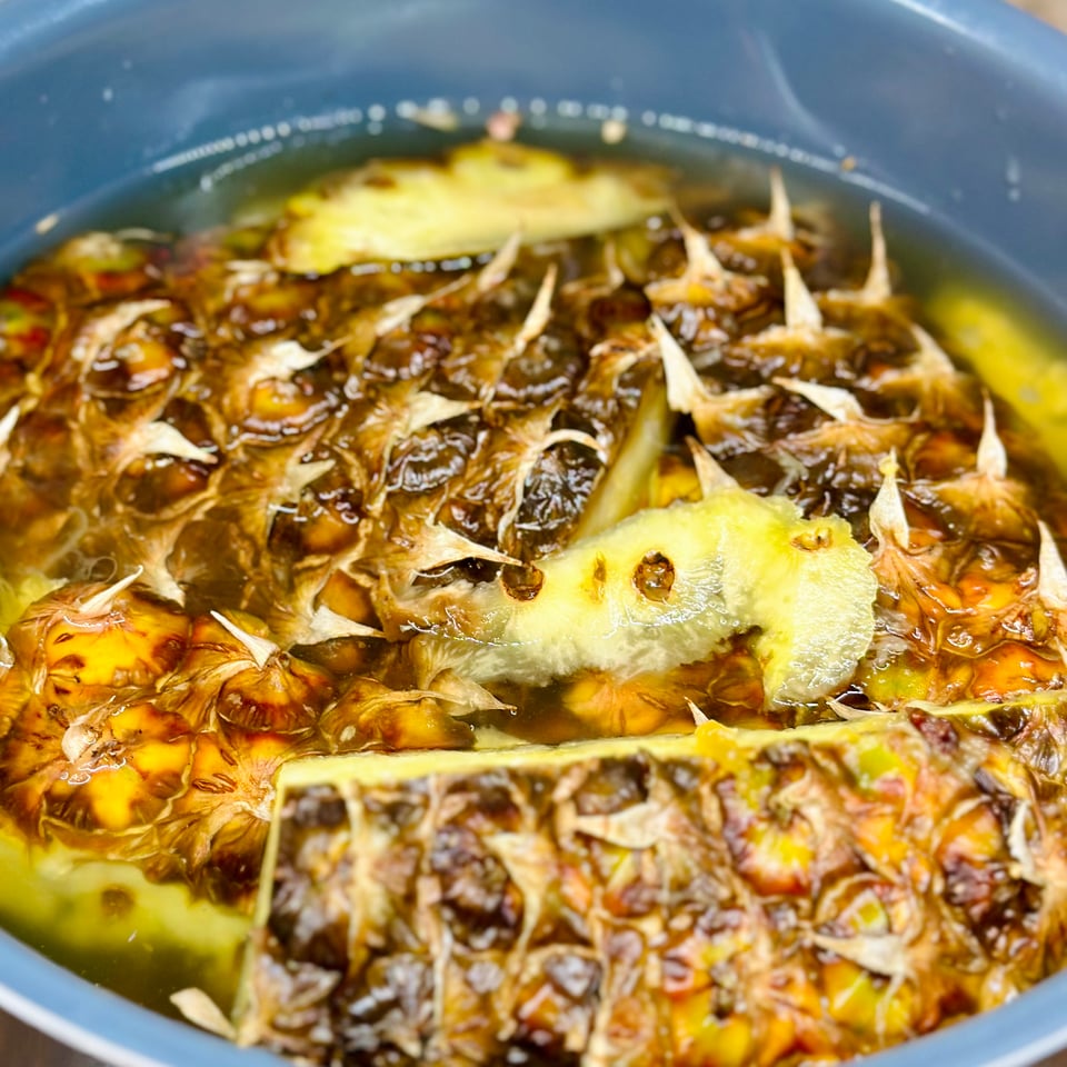 A photo of pineapple rinds in a pot, covered with water