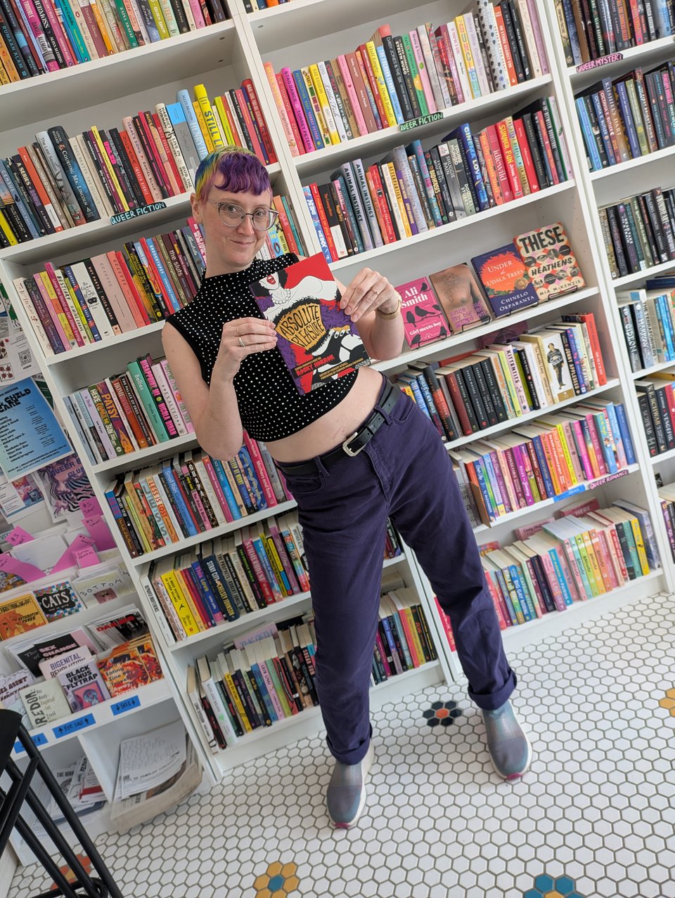 Margot posing with ABSOLUTE PLEASURE in front of bookshelves at Hive Mind