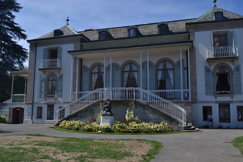 An ornate building with a sculpture and a grand entrance with two staircases.