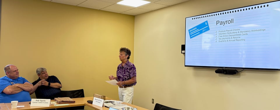 Lisa stands in front of the room, talking about payroll services.