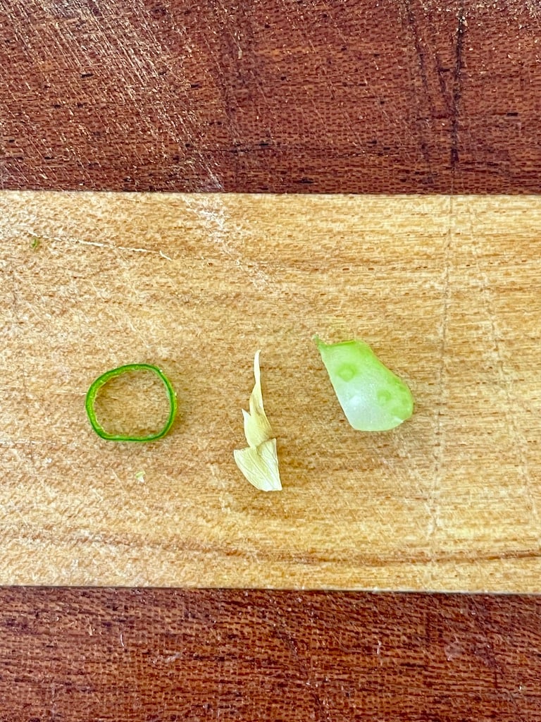 A small slice of spring onion, celery leaf and celery stalk on on chopping board