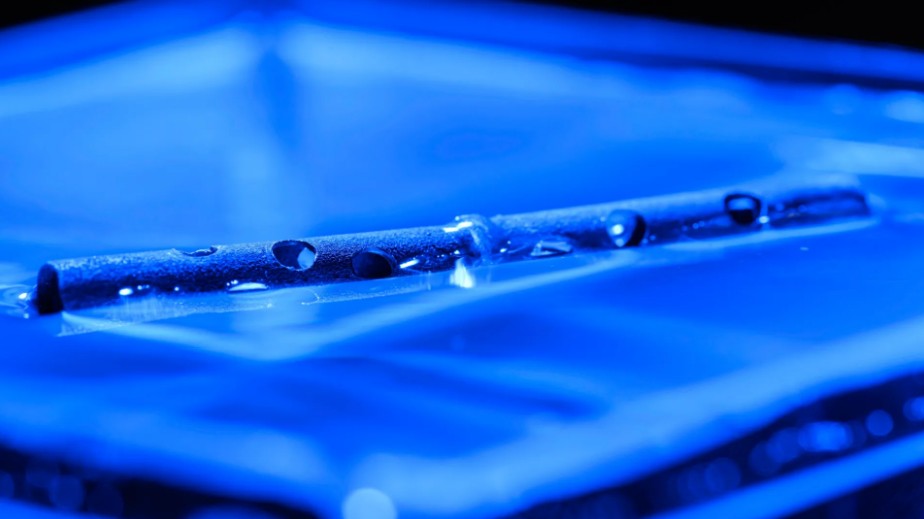 An aluminum tube with numerous holes drilled in it floating on the surface of water.