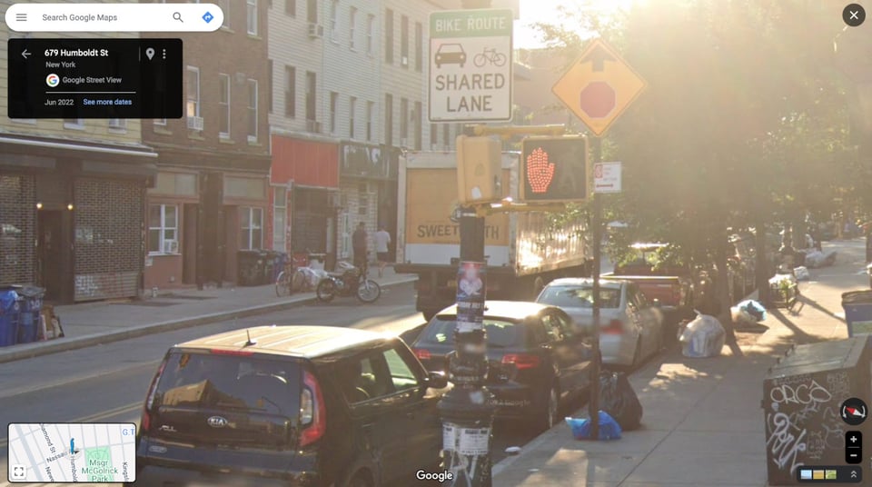 A screenshot from Google maps street view, showing a Brooklyn street with stores lining the sidewalk and cars parked on the curb. There is a commercial truck in the road facing away from us -- it has the words "sweet tooth" printed on the back, but there's a telephone pole in front of "tooth" so you can only see "sweet"