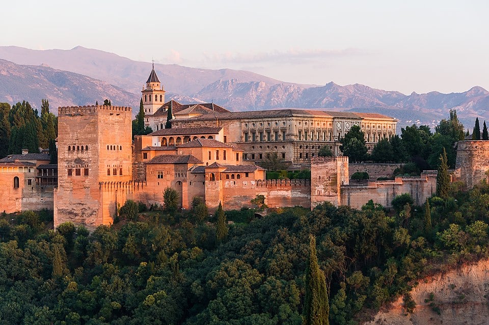A European palace surrounded by mountains in the background and greenery in the foreground