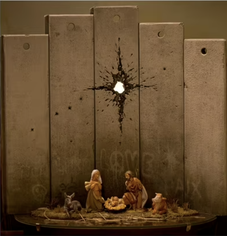 A manger scene in front of a replica of the separation wall pierced by a bullet hole, with a star shape around the hole