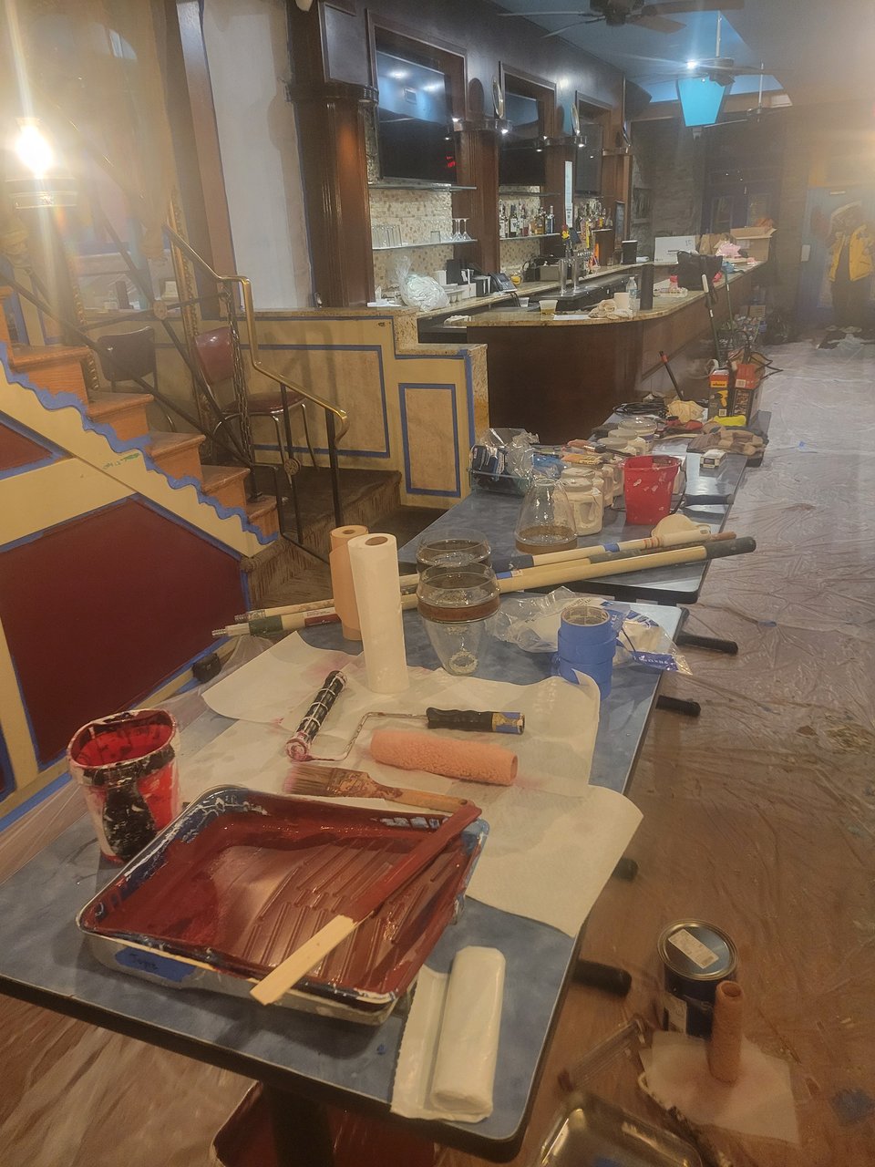 A display of all the painting, scraping, and various other tools lined up on restaurant tables that we've been using to change up the bar. Lots of rollers, poles, blue tape, trays, etc.
