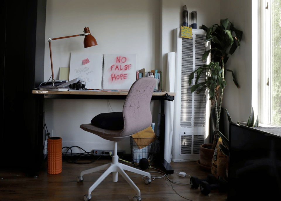 a home office with desk and chair and an open notebook that reads "no false hope"