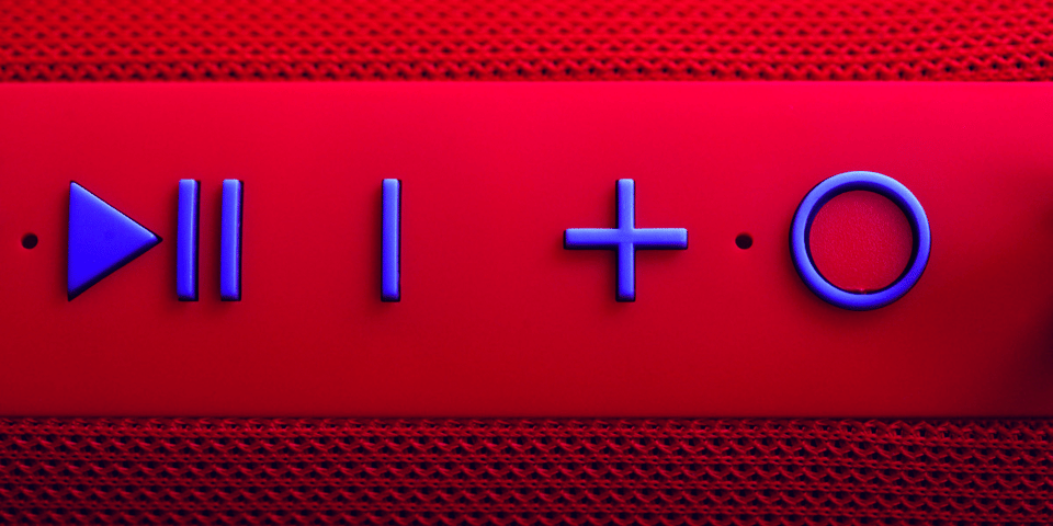 A close up of a red portable speaker with blue buttons.