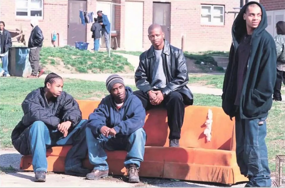 Wallace, Poot, D'Angelo, and Bodie from The Wire, hanging out near an abandoned orange coach