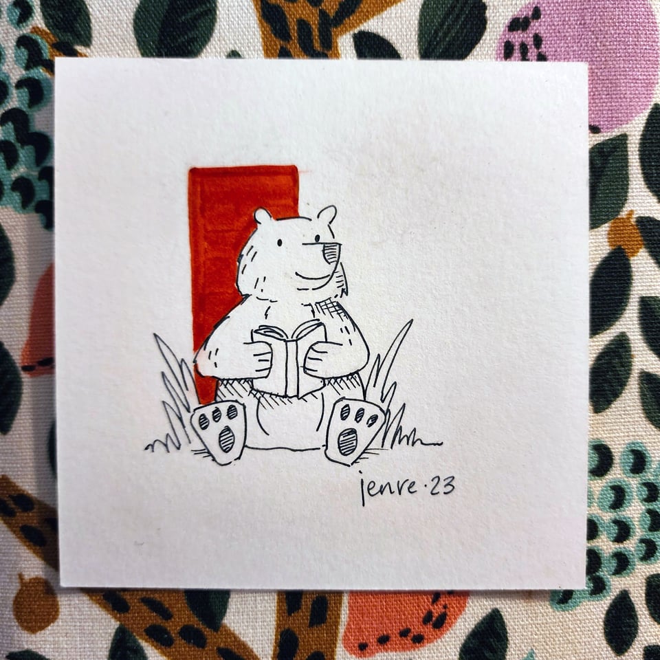 Pen and ink drawing of a happy bear reading a book.