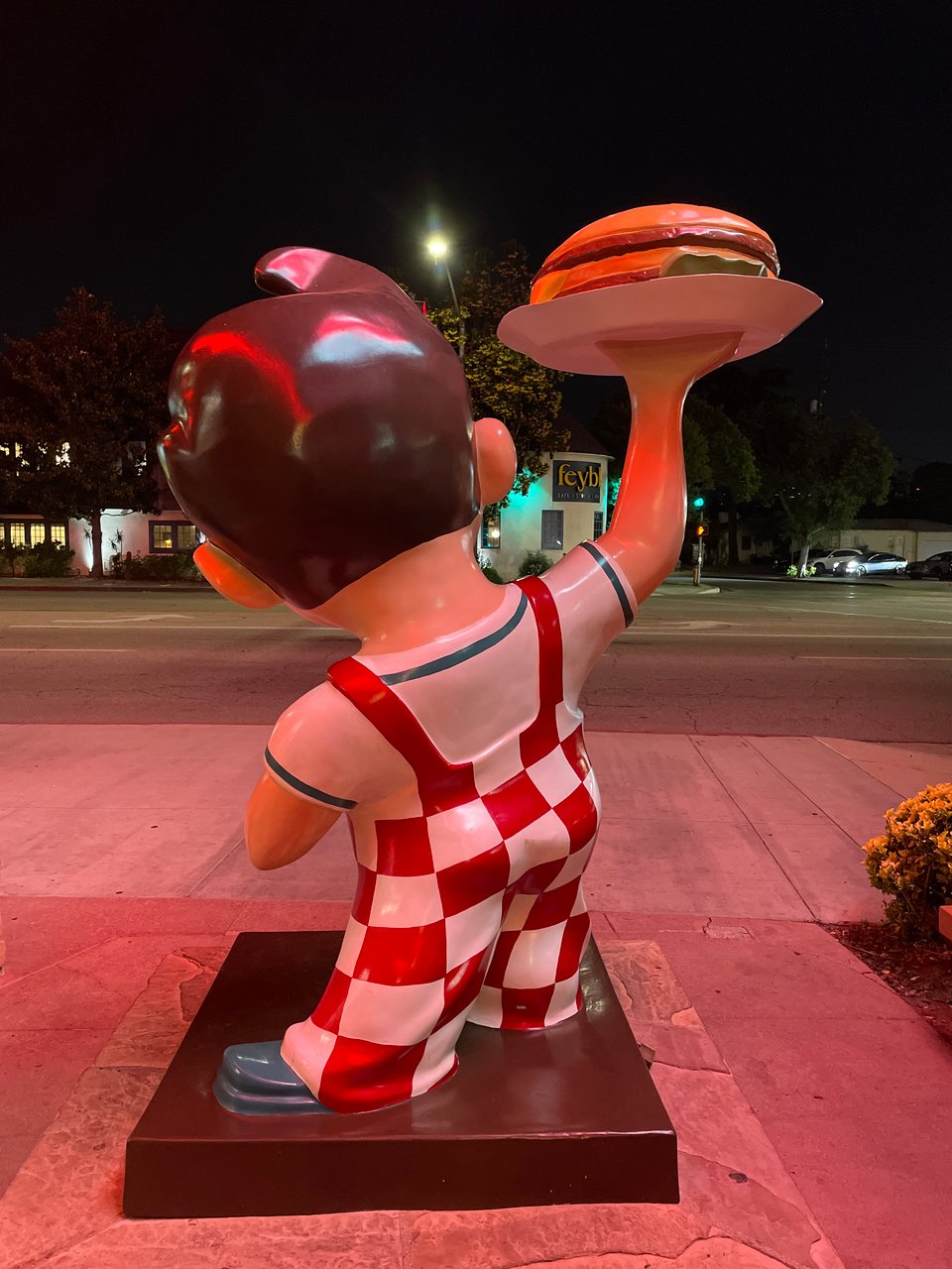 The famous Big Boy statue outside Bob's Big Boy in Burbank. The statue is shot from behind, lit by neon lights in the dark night