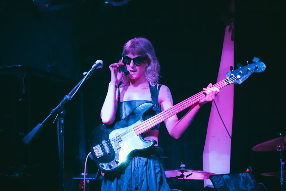 Lotus holds the bass, wearing cool angled sunglasses and answering a retro telephone