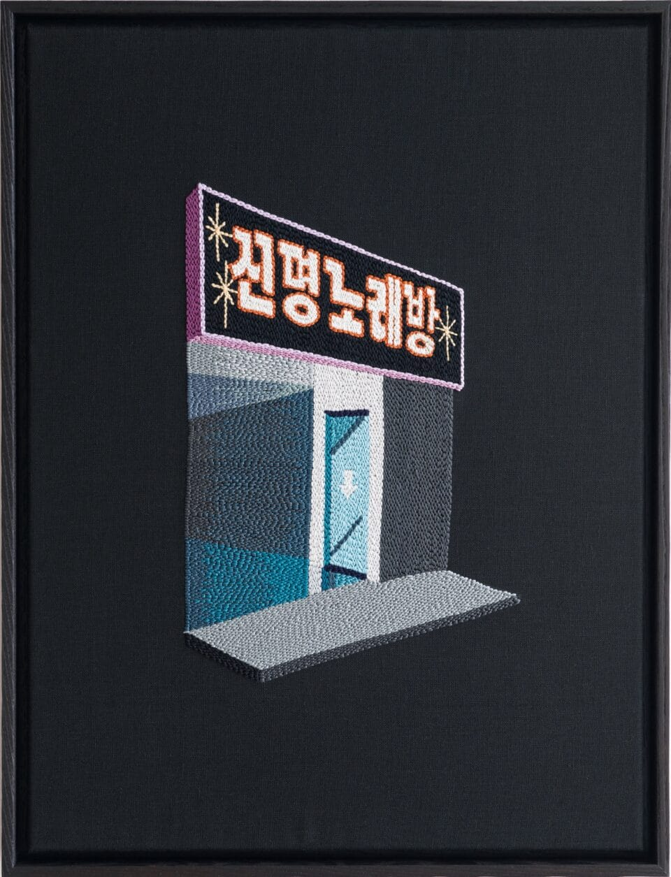 An embroidered image of a shop front. The name of the shop is in thick Korean white lettering with small star-shaped art-deco decorations, and there are grey and blue windows and a door with an arrow pointing downward. In front there's a small piece of grey sidewalk. All around is pitch black, as if the store were floating in space