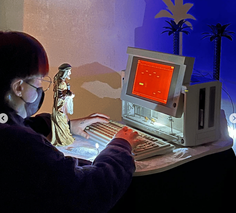 a person using an old fashioned computer next to a biblical figurine