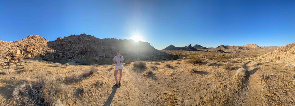 A panoramic view of a a woman in a bright desert landscape