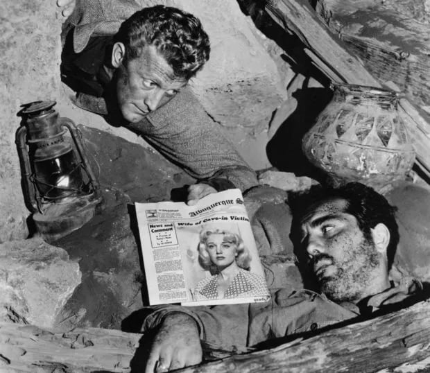 Still from Ace in the Hole featuring two men trapped in a mine looking at a newspaper