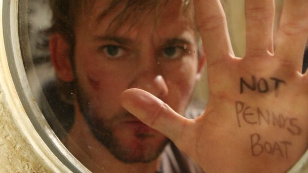 A white guy behind a porthole holds up a palm with "NOT PENNY'S BOAT" written on it.