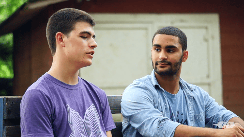 Young Yatú and Norm sitting next to each other on a bench outside.