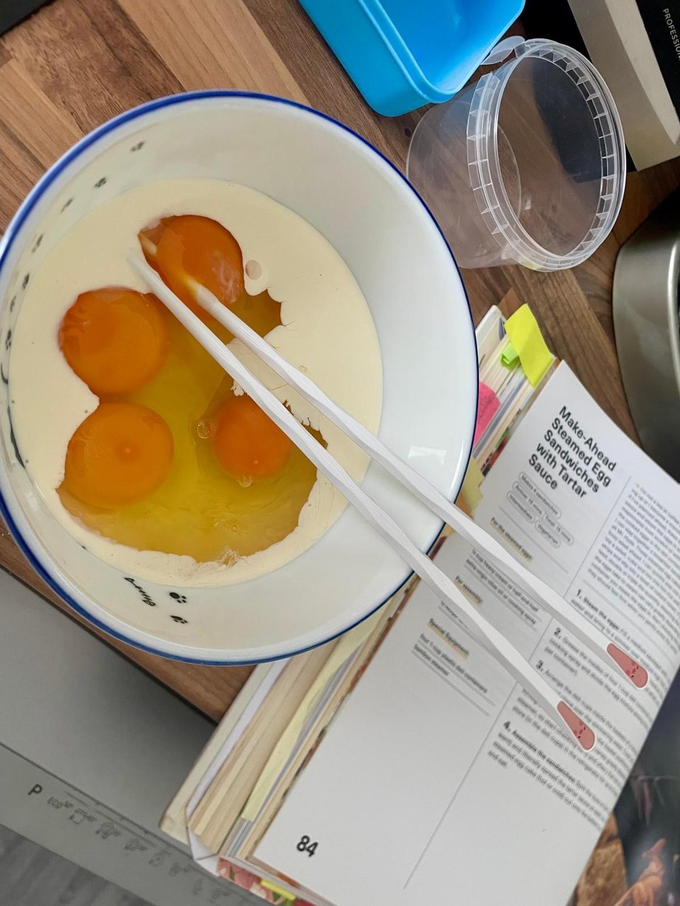 Four eggs cracked into a bowl with cream and chopsticks