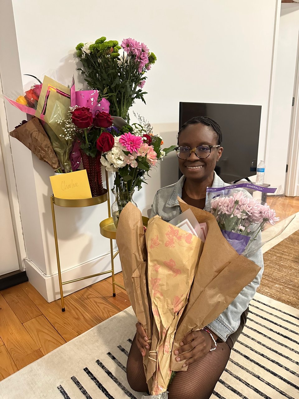 A black woman holding several flower bouquets.