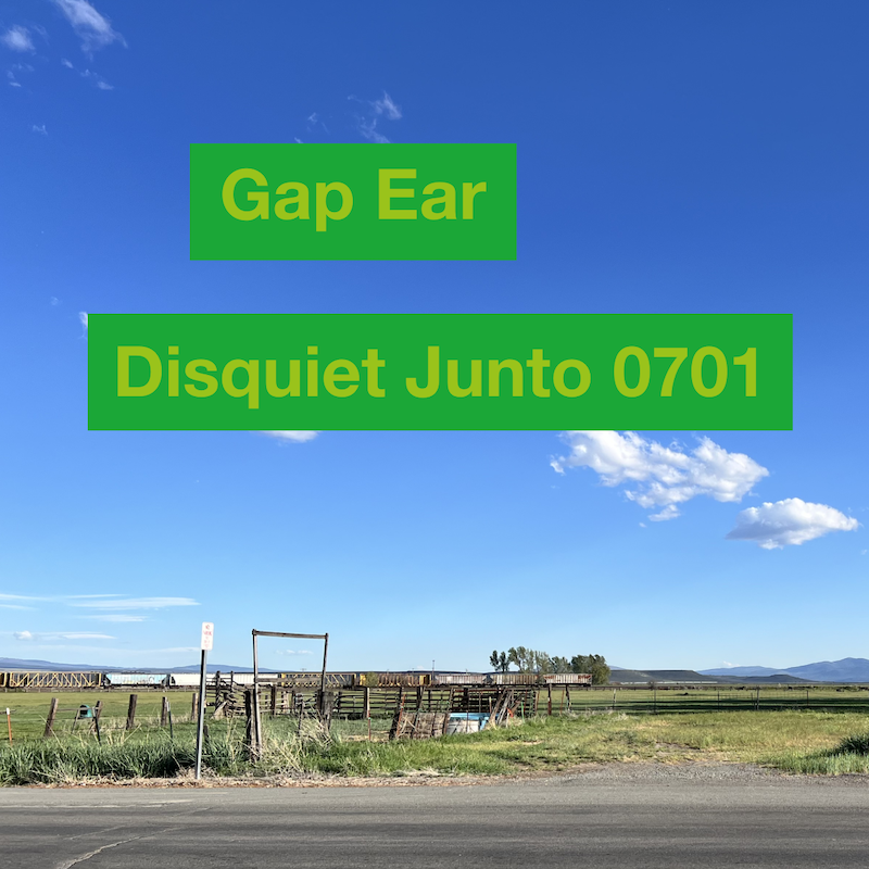 The photo shows a blue sky with bright white clouds over a flat landscape with hills in the distance, plus the name and number of the project