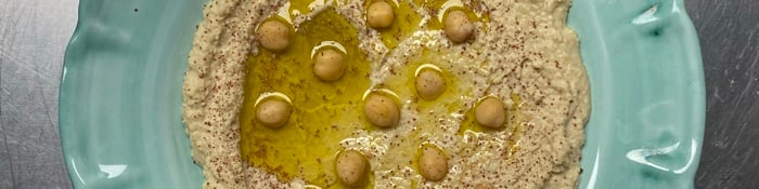 Hummus with olive oil and chickpeas on a sea-green plate