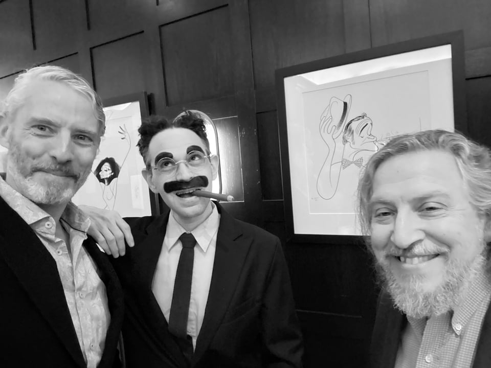 B/w photo of 3 white men, the middle of whom is a Groucho Marx impersonator