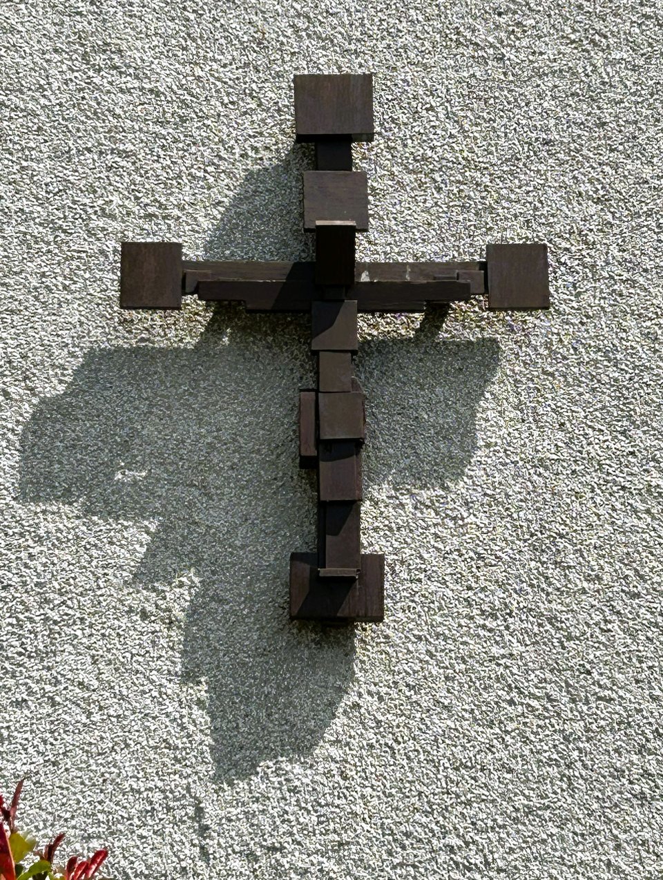 A blocky dark brown wooden crucifix, in which squared blocks represent both the cross and the body of Christ.
