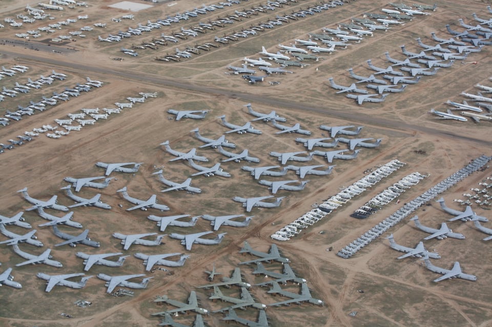 An aerial image of of several massive brown fields, upon which are parked dozens and dozens of military fighter jets.