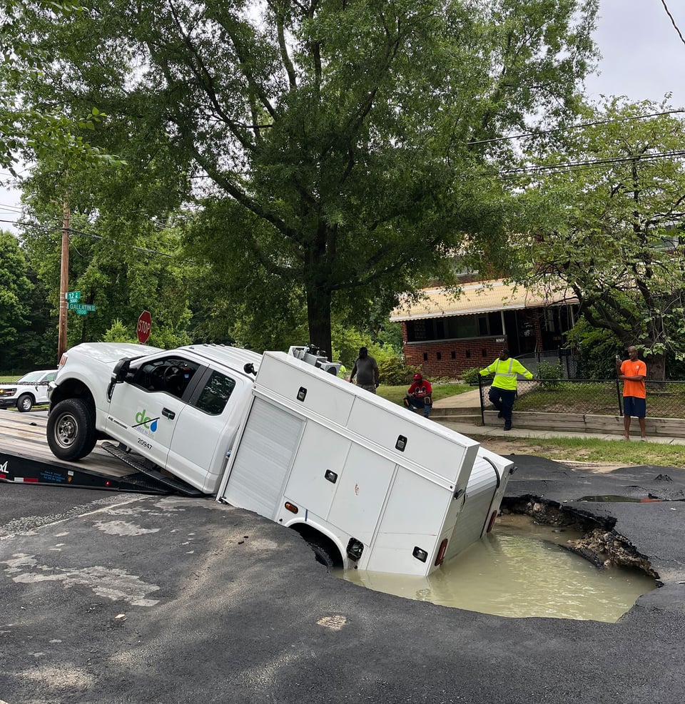 DC Water service truck getting pulled out of a water-filled sinkhole.