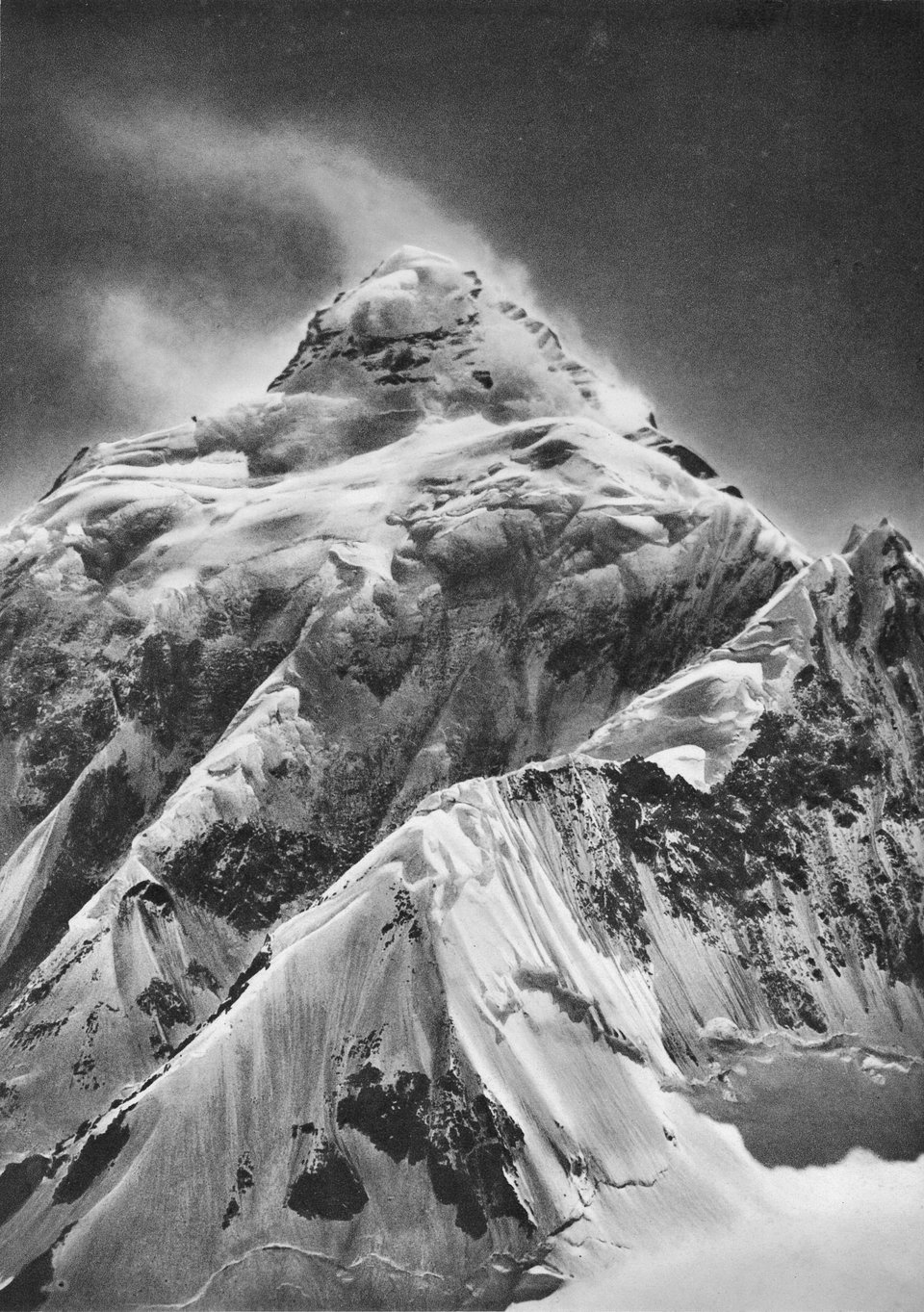 A black and white picture of the mountain K2, gleaming in light and shadow.