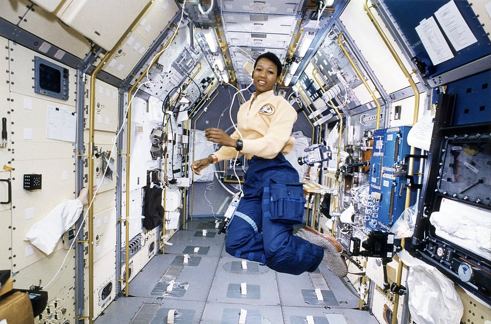 Mae Jemison in her astronaut's uniform, floating in zero gravity on the Space Shuttle.