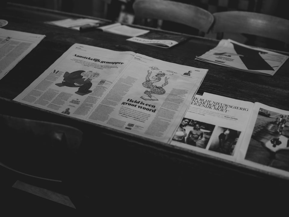 A row of newspaper dispensers. Photo by Nikolay Loubet on Unsplash.